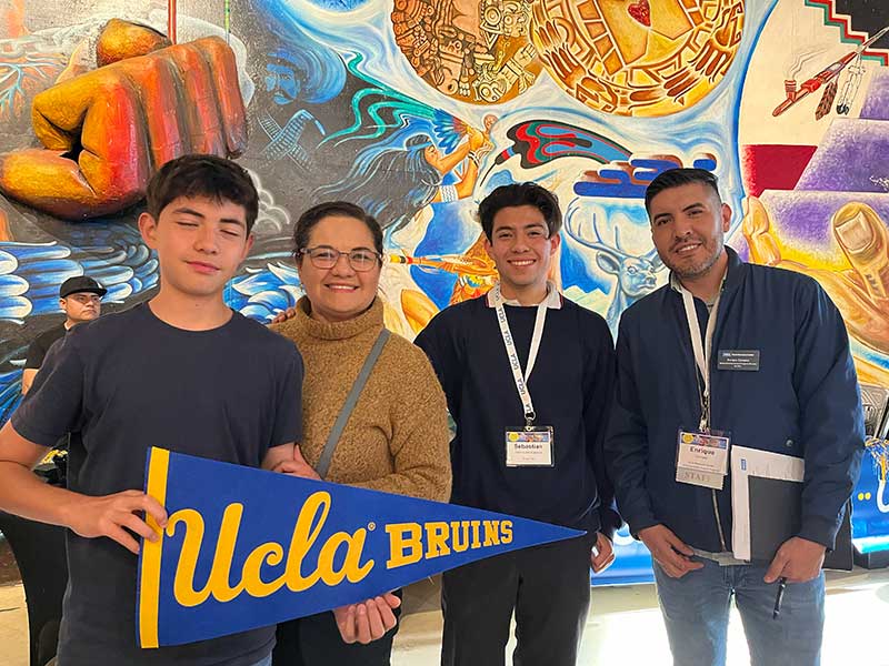 UCLA admitted student and his family post with Enrique Campus at yield event in San Diego.